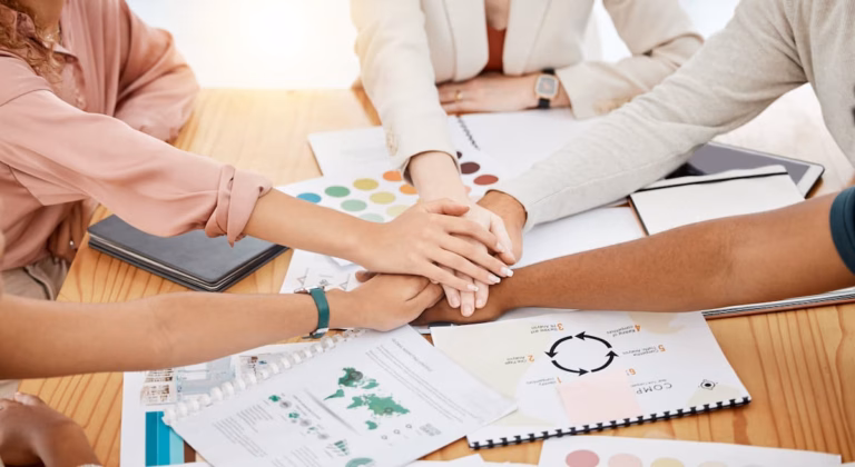 workers joining hands on a desk